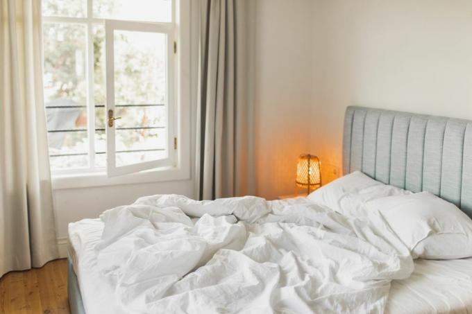 מיטה בחדר מלון עם שמיכה מקומטת מעוררת קונספט נסיעות וחופשות