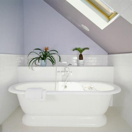 אמבטיה תחת צוהר בחדר אמבטיה בעליית הגג עם קירות סגולים לילך